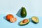 Composition of fresh fruits, mandarin, whole avocado and two halfs of cutted avocado on two-colored background