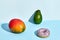 Composition of fresh fruits and sweets, donut mango and avocado on two-colored background