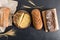 A composition of fresh homemade bread of various shapes on a black background with ears of wheat