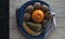 Composition of fruits on a decorative blue platter on a wooden board with a black cloth in the background