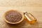 Composition of glass oil jars, wooden bowl and scoop with flax seeds, selective focus