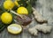 The composition of glass vase with floral honey and wooden spoon with lemon and ginger on a wooden background