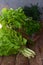 Composition of green herbs and vegetables. Organic spring mix for salad on brown wooden background. Lettuce, parsley, dill, chard.