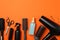 Composition hairdresser accessories on orange background, space for text