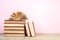 Composition with hardback books, fanned pages on wooden deck table and pink background. Books stacking. Back to school. Copy Space