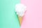 Composition of ice cream cone with pink wisp of bast on a light blue background