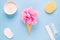 Composition of ice cream cone with pink wisp of bast on a light blue background