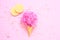 Composition of ice cream cone with pink wisp of bast on a light pink background
