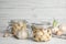 Composition with jars of pickled garlic on white table