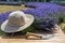 Composition of lavender bouquet, large  sunscreen hat and a sickle on a wooden table