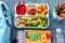 Composition with lunch box, appetizing food and stationery on wooden background