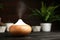 Composition with modern essential oil diffuser on black wooden table against dark background