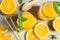 Composition with orange pieces, mint, tubules, wooden juicer and glass jars with fresh orange juice on grey background