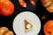 Composition of piece of pumpkin pie on plate and leaves with pumpkins on black background