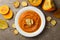 Composition with plate of pumpkin puree with croutons on gray background