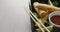 Composition of plate with spring rolls and chilli sauce with chopsticks on grey background