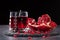 A composition of a pomegranate drink and cut garnet on a black background. Healthful and fresh red cocktails.