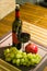 Composition of pomegranate, yellow muscat grape, glass and bottle of red wine on a wooden board