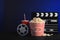 Composition with popcorn, cinema clapperboard and film reel on table against color background
