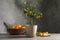 Composition with potted citrus tree and fruits on table against grey background