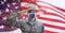 Composition of saluting male soldier wearing face mask, against waving american flag