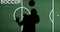 Composition of silhouettes of football player with ball over soccer text on football pitch