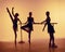 Composition from silhouettes of three young dancers in ballet poses on a orange background.