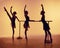 Composition from silhouettes of three young dancers in ballet poses on a orange background.