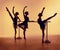 Composition from silhouettes of three young dancers in ballet poses on a orange background.