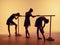 Composition from silhouettes of three young dancers in ballet poses on a orange background.