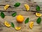 Composition of slices, whole of orange fruits with green leaves on wooden background