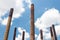 Composition of smokestacks against a blue sky with clouds seen from a low angle