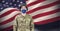 Composition of soldier wearing face mask standing to attention, against waving american flag