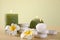 Composition of spa stones, flowers and burning candles on wooden table against light green