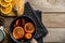 Composition with spicy mulled wine, oranges and pine cones on wooden background.