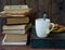 The composition of a stack of old books, tea cups, glasses and plates of sugar cookies on a wooden background. Vintage photo. Side