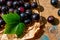 Composition with sunlit ripe black currant berries on wooden table with paper and green leaf. Macro