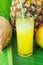 Composition Tall Glass with Freshly Squeezed Tropical Fruit Juice with Straw Pineapple Coconut Mango on Large Green Palm Leaf