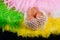 Composition of three beige eggs laying in netting on colored feather background