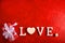 Composition for Valentine`s Day on a red background with white letters and a heart. Top view.