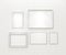 Composition of white blank picture frames on white brick wall with spotlights