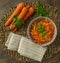 Composition of whole and julienned carrots on a straw mat with parsley leaves and beige napkin