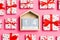 Composition of wooden calendar and holiday white gift boxes with red hearts on colorful background. The fourteenth of february.