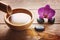 Composition on a wooden table with a bamboo stem and a bowl of water, stones for spa procedures and a bright orchid flower.