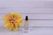 Composition a yellow flower and serum in a glass test tube on a white wooden background. Copy space