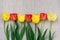 Composition Yellow Red Tulips Arranged in Border on Light Grey Rough Linen Cloth Minimalist Style Mother`s day Birthday Easter