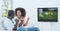 Compostion of diverse couple watching football match on tv on white background