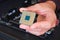 Computer chip CPU held by a man with his fingers - close up of the pins grid