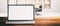 Computer laptop with blank screen, on a wooden desk, blur office background, banner