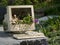 Computer screen and keyboard used as decoration in a garden with various flowers